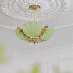 A light green shell-shaped glass pendant light with intricate gold leaf details against a white ceiling.