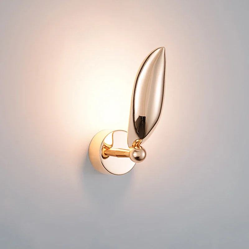 Gold wall sconce with a leaf-like design on a light gray background