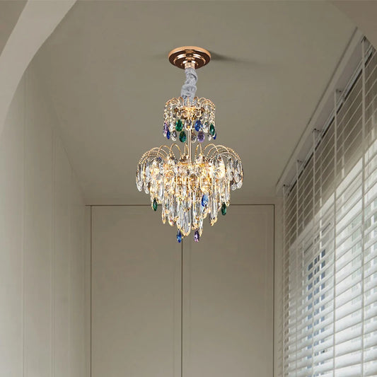 A gold multi-tier crystal chandelier with clear and colored crystals hanging from a ceiling.