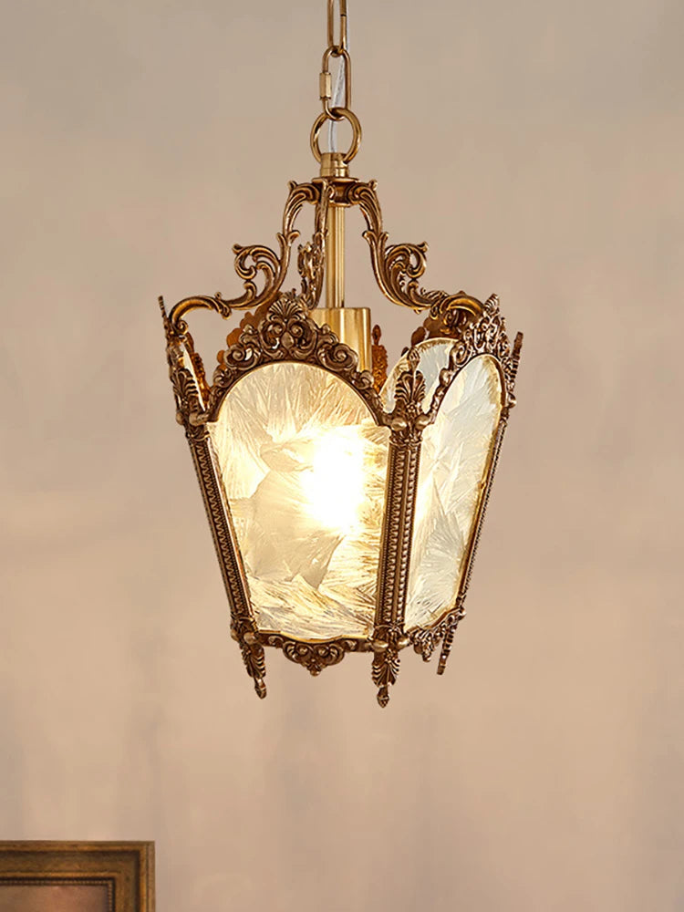 Decorative pendant light with ornate brass fixture and textured glass shade on a neutral background.
