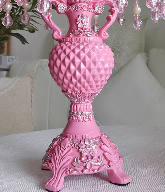 Pink decorative lamp with intricate designs on a white surface.