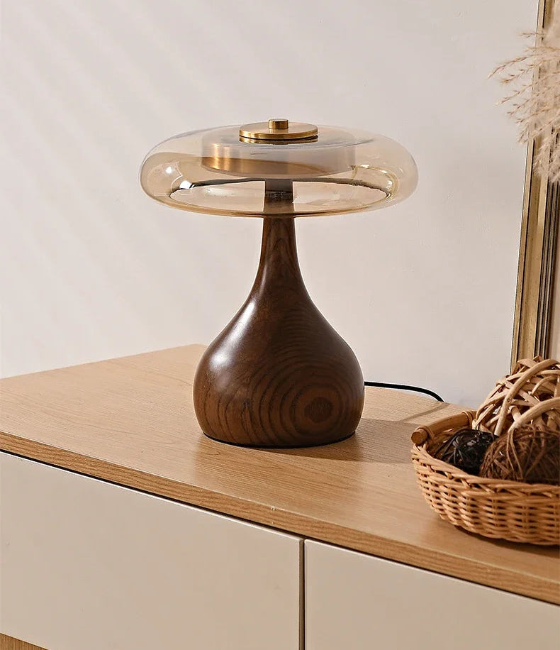 Wooden table lamp with glass shade on a wooden surface