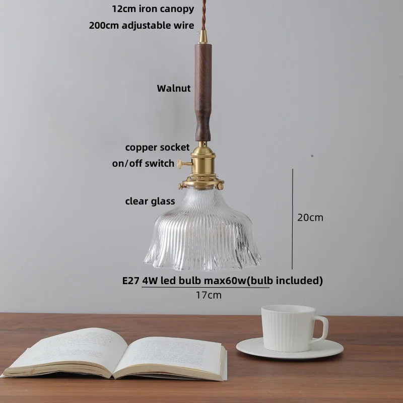 Pendant light with clear glass shade on a wooden surface with measurements and details.