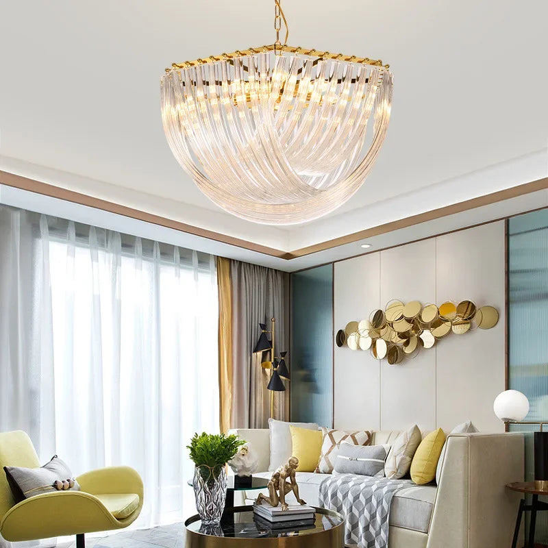 A luxurious gold crystal waterfall chandelier with a rounded design, featured in a well-decorated living room with plush seating.