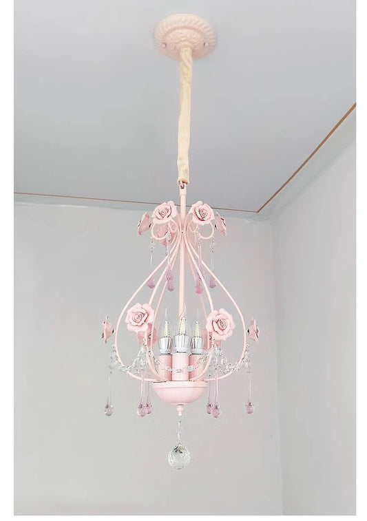 A pink crystal chandelier with rose accents hanging from a ceiling.