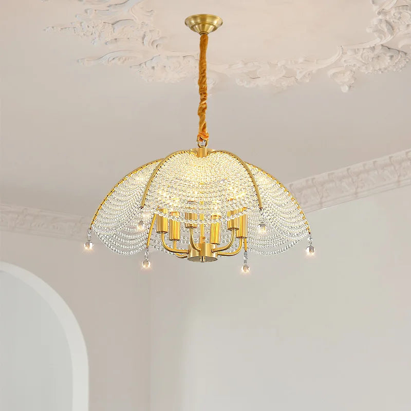 A full room shot showing a gold crystal fan-shaped chandelier as the focal point, illuminating a space with a refined atmosphere.