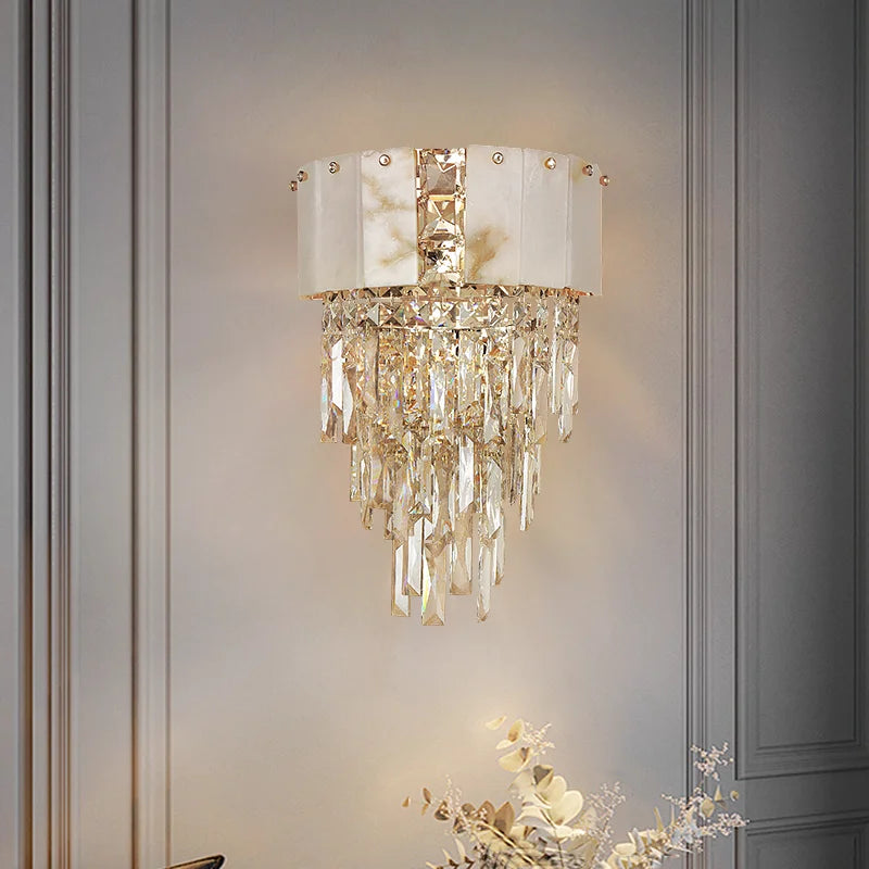 Decorative wall light fixture with crystal details on a gray wall.