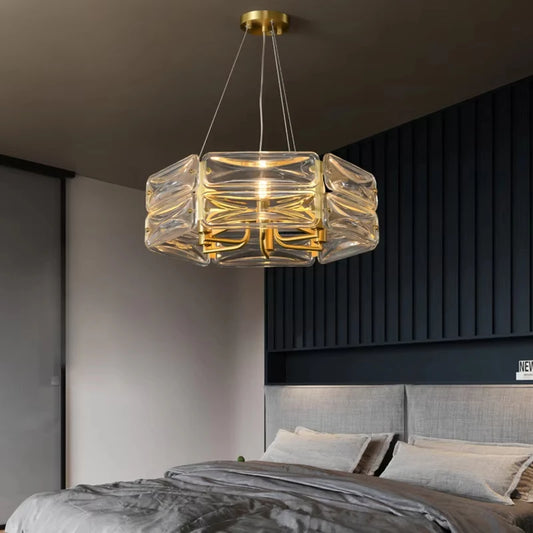 A gold and crystal chandelier with stacked cube-shaped crystals hanging in a modern bedroom.