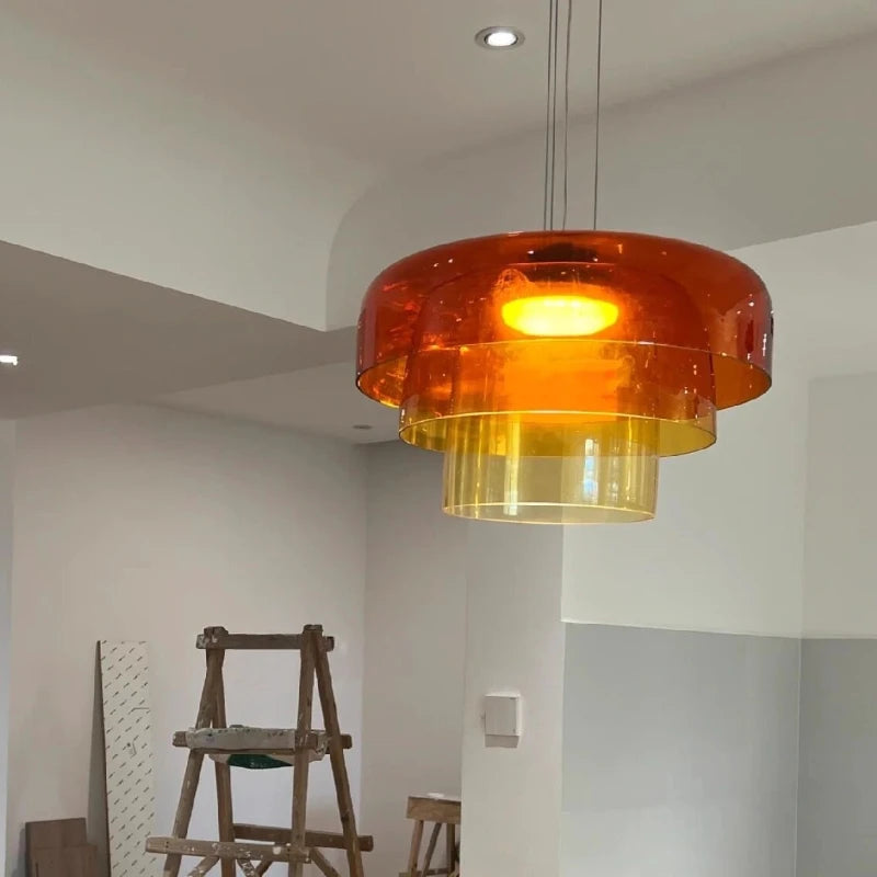 Orange pendant light in a room with a ladder and wall art.