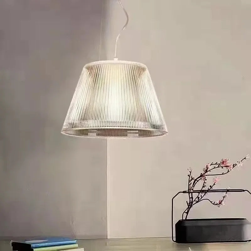 A single clear pleated glass drum pendant light hanging in a minimalist room.