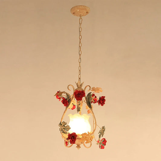 A single gold floral pendant light with red rose accents and a frosted glass shade, hanging from a chain against a plain background.
