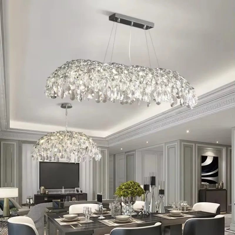 A large, multi-tiered chrome chandelier with cascading crystals over a dining room table.