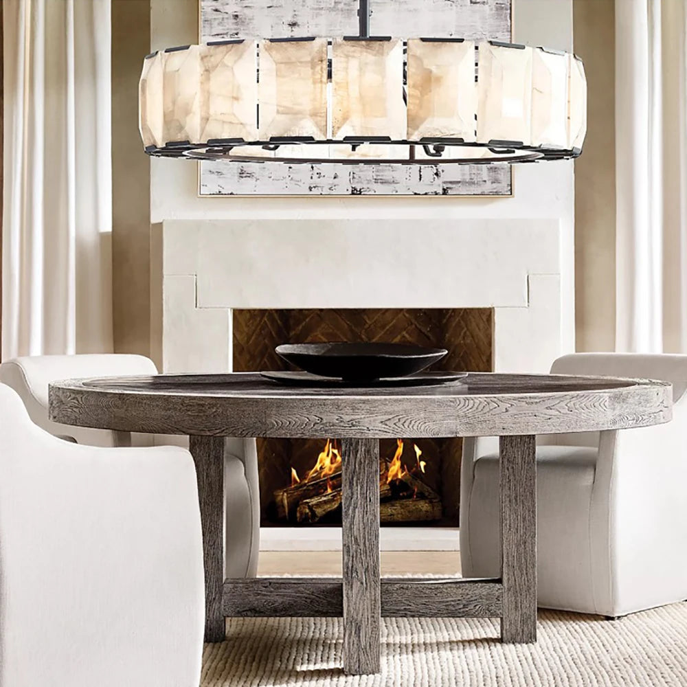 Round wooden table in front of a fireplace with a chandelier above