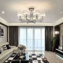 A polished chrome multi-arm crystal chandelier installed in a modern living room with large windows.