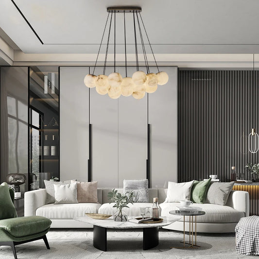 A modern living room with a gold chandelier featuring multiple suspended marble-effect globes.