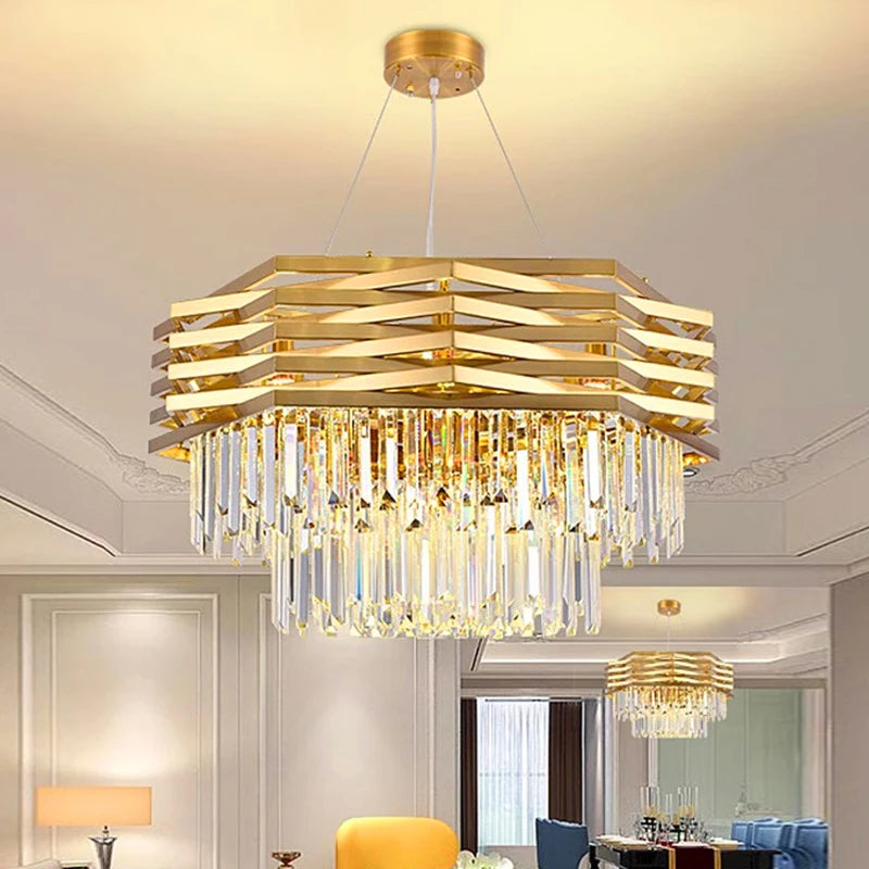A gold tiered crystal chandelier illuminated in a dining room setting with blue chairs and a dark table.