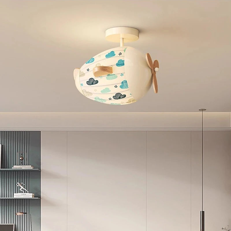 Interior view of a child's bedroom featuring an airplane ceiling light with a cloud pattern.