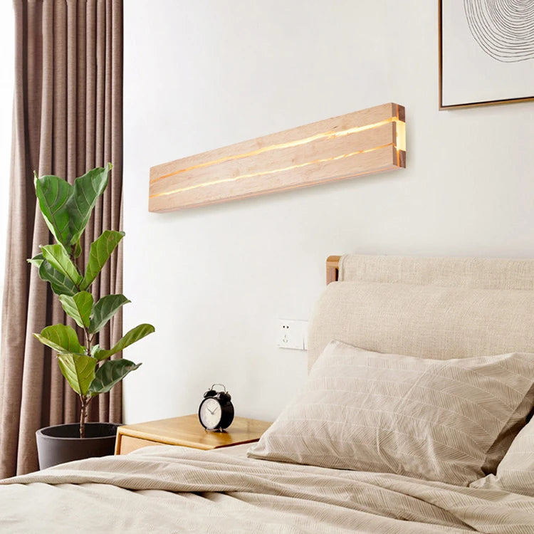 Modern bedroom with a bed, plant, and wall-mounted light fixture.