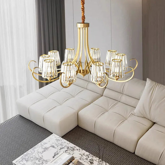 Wide shot of a polished gold chandelier with crystal accents, suspended above a sectional sofa in a contemporary living room.