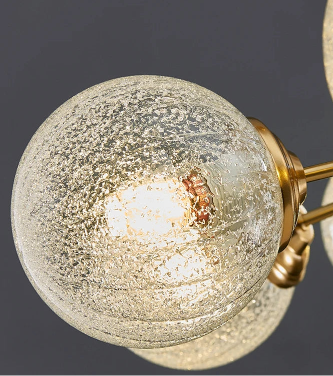 Close-up of a modern chandelier with glass globe shades and gold fixtures on a dark background.