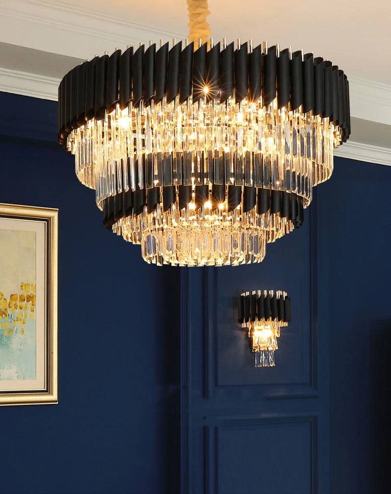 Chandelier hanging from a ceiling with a wall-mounted light fixture below against a blue wall.