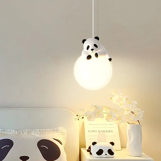 Close-up of a white globe pendant light with a white panda figurine perched on top, illuminated in a child's room setting.