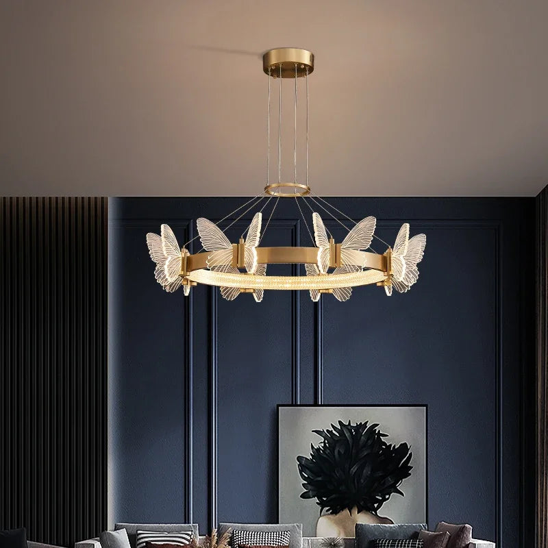 A modern gold ring chandelier with clear crystal butterfly accents hanging from a ceiling.
