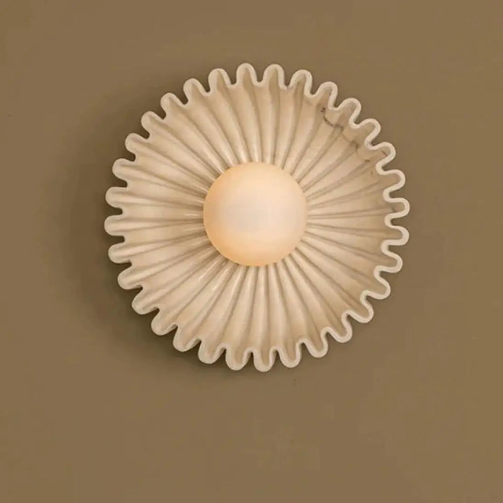 Cream-colored carved wall sconce with a light brown globe light in the center.