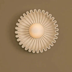 Cream-colored carved wall sconce with a light brown globe light in the center.