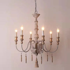 Close-up view of a distressed wood chandelier featuring carved details and candle-style light fixtures against a neutral background.