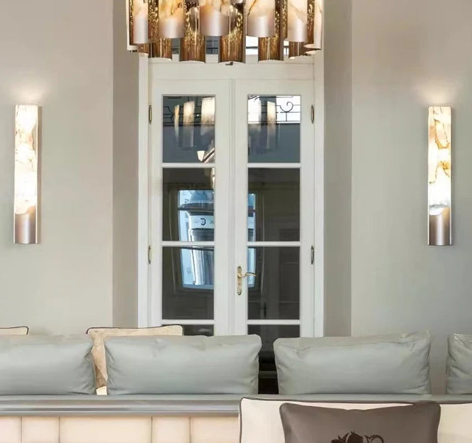 Modern living room with a chandelier, wall lights, and a sofa.