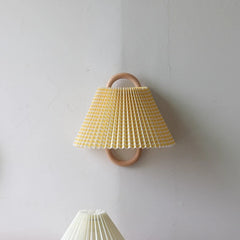 A yellow and white checkered fabric cone shade wall sconce with a natural wood hoop frame mounted on a textured white wall.