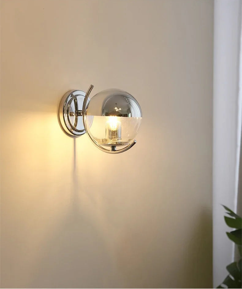 Wall-mounted light fixture with glass shade on a neutral wall.