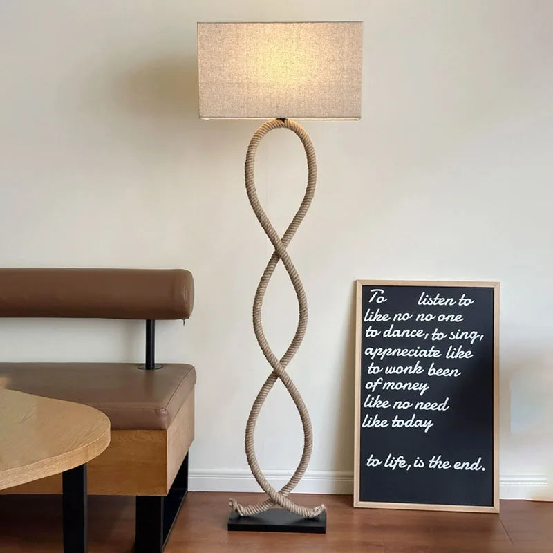 Rope-style floor lamp in a room with a bench and framed quote on the wall.