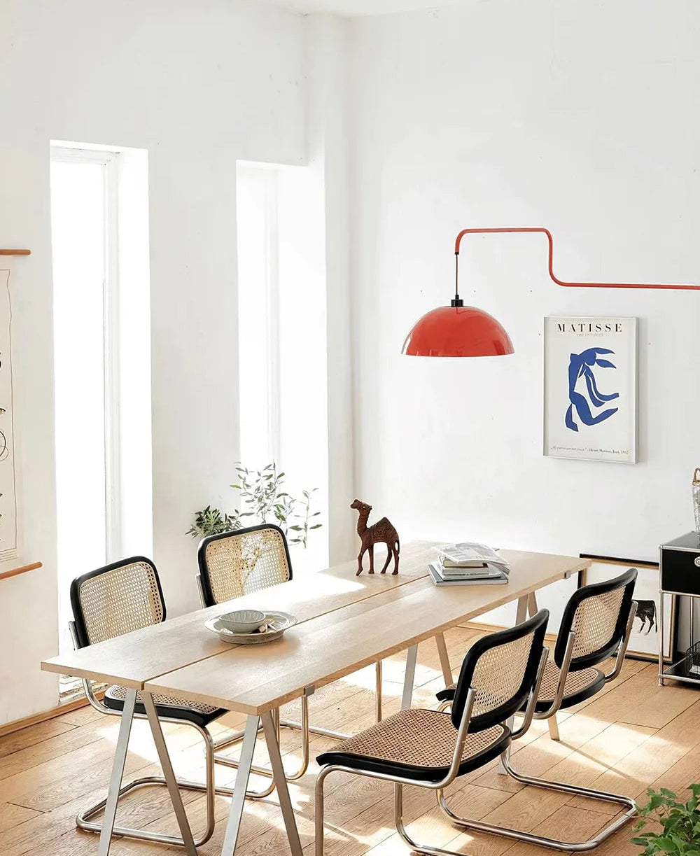 Modern dining room with a wooden table and chairs, red pendant light, and abstract art on the wall.