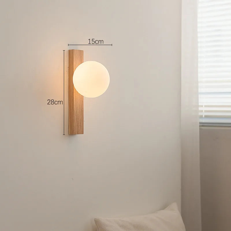 A wood and frosted glass sphere wall sconce with dimension labels indicating a height of 28cm and width of 15cm on the wooden base.