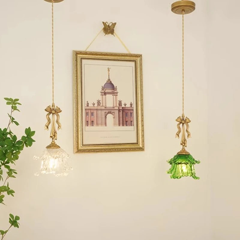 Two hanging pendant lights with gold fixtures and glass shades on a wall with a framed picture.