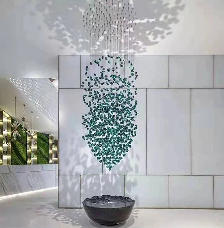 Modern interior design with a chandelier, water feature, and green wall art.