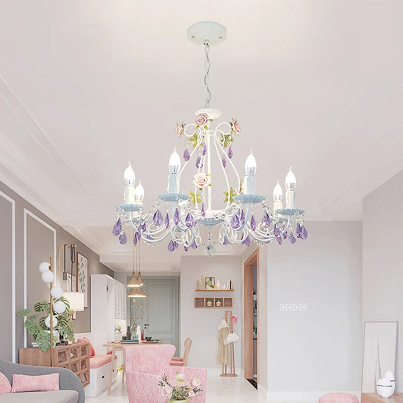 White wrought iron chandelier with floral and crystal details hanging in a living room.