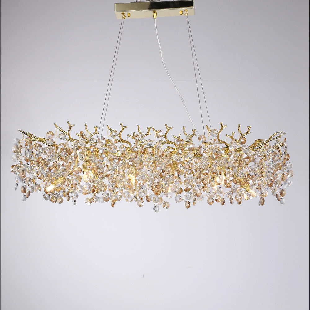 Close-up view of a gold crystal chandelier with a branch-like frame and clear faceted crystal accents on a white background.