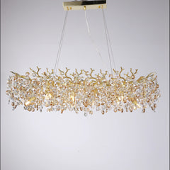 Close-up view of a gold crystal chandelier with a branch-like frame and clear faceted crystal accents on a white background.