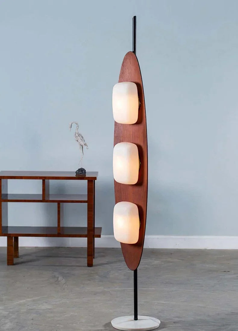 Modern floor lamp with three spherical lights in a room with a wooden side table.