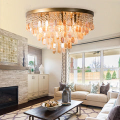 Gold shell and crystal cascading pendant light installed in a modern living room with a stone fireplace and sofas.