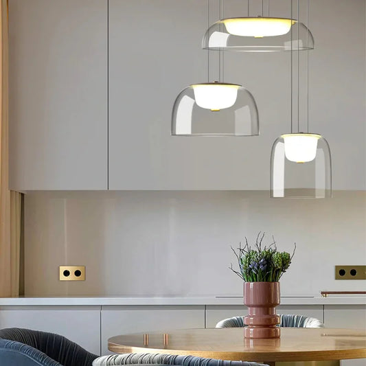 A cluster of three clear glass dome pendant lights with gold accents hanging above a kitchen island.