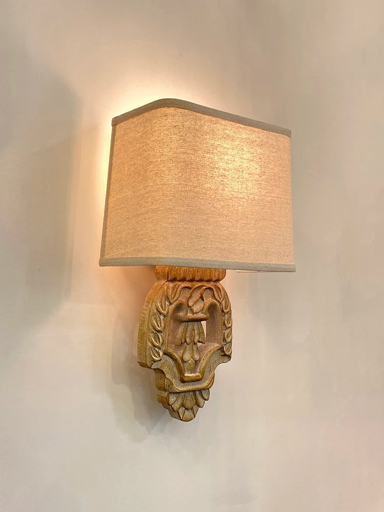 Side view of a vintage wood wall sconce with a rectangular fabric shade and carved decorative base.