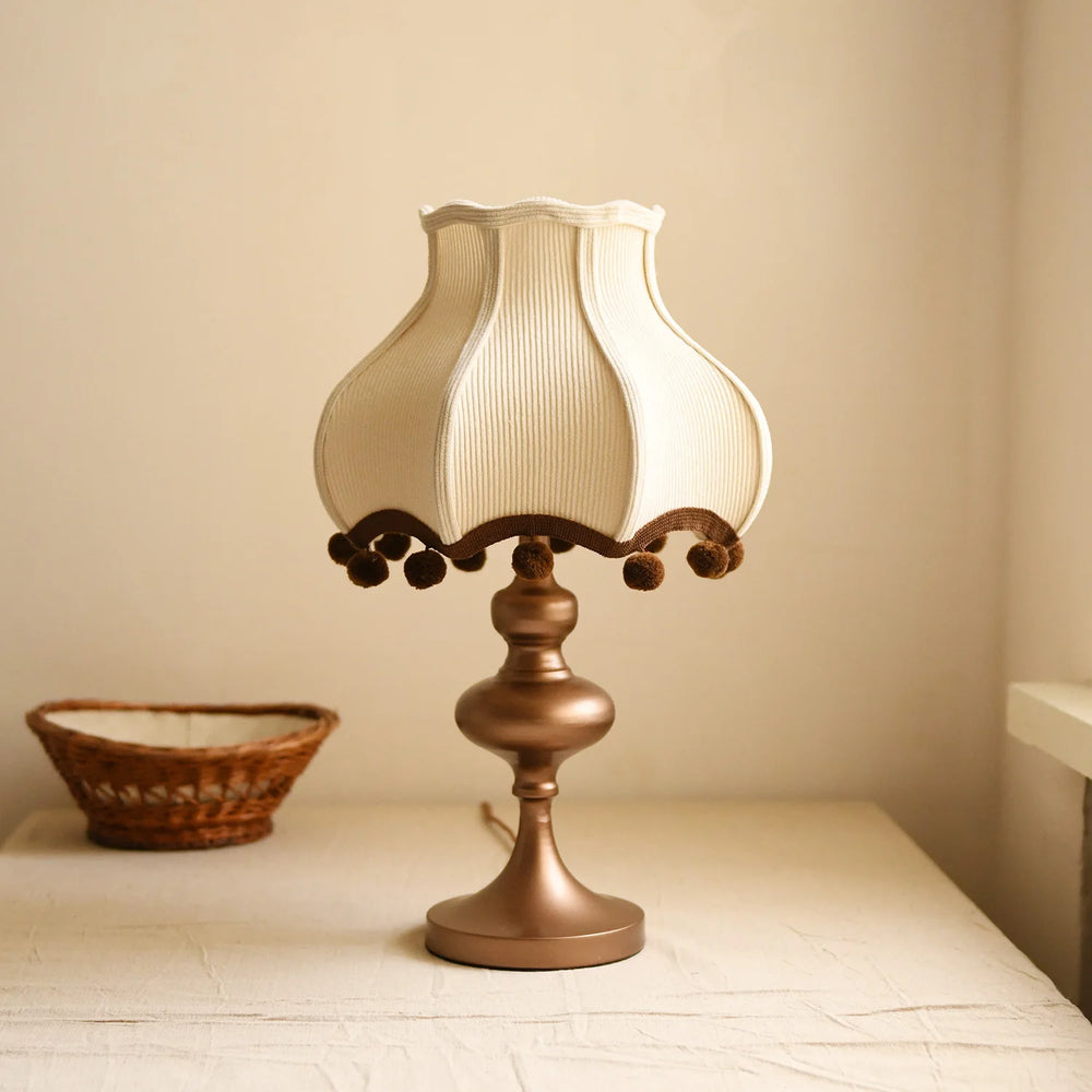 Table lamp with decorative shade on a surface against a plain background