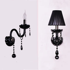 Close-up of a black wall sconce with crystal accents and a single flame-shaped LED bulb.