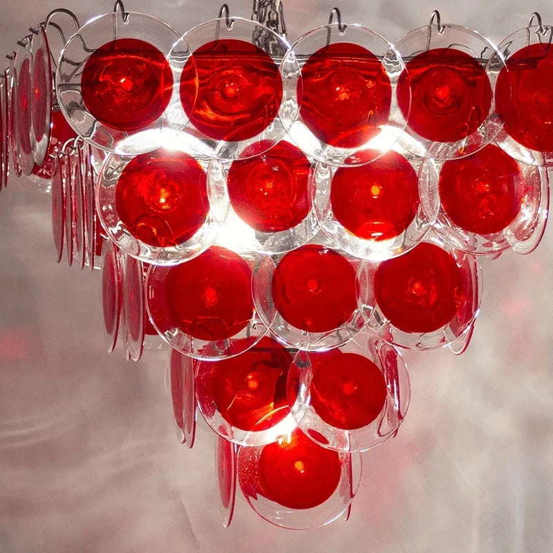 A view from above of a square-shaped chandelier frame adorned with red glass discs.