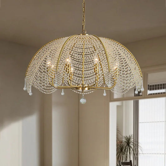 View of a gold crystal waterfall chandelier hanging in a well-lit room with a window.