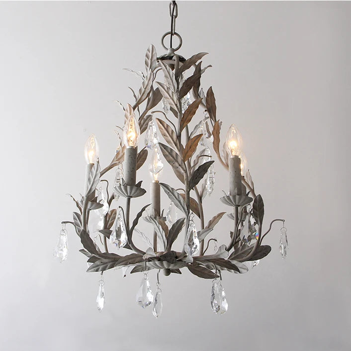 Grey wrought iron leaf chandelier with clear teardrop crystals hanging from candle-style lights, against a white background.
